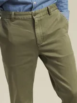 Pantalón de vestir color beige, de corte recto, con bolsillos laterales y traseros. Se ajusta a la cintura con cinturón de cuero marrón.