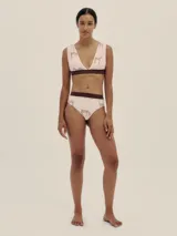 Bikini de dos piezas con estampado de lunares negros sobre fondo blanco. El corpiño es de corte triangular con tirantes finos y se ata en la espalda. La bombacha es de corte alto a la cintura con una banda ancha negra.