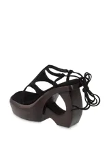 Sandalias negras de gamuza con plataforma de madera y tiras que se atan al tobillo.