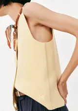 Chaleco de punto sin mangas en color amarillo suave, con cuello en V y cierre frontal de botones al tono. Presenta un diseño clásico y minimalista con un pequeño bordado decorativo en la parte inferior.