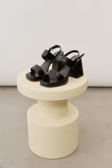 Sandalias de cuero negro con plataforma delantera, taco ancho y tira ajustable en el talón.