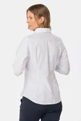 Camisa de tejido Oxford lisa y color blanco, con cuello camisero, cierre frontal de botones y mangas largas con puños abotonados.