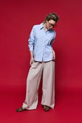 Pantalón tiro alto color beige, de calce amplio y diseño wide leg con pinzas delanteras, bolsillos laterales y presillas para cinturón.