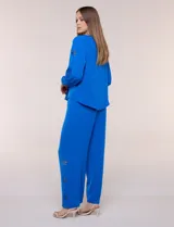 Blusa azul de corte holgado y fluido, con escote en V y mangas largas raglán que presentan detalles de calados con forma de flores y puños elastizados.