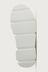 Zapatilla de estilo urbano con suela de plataforma voluminosa y diseño irregular. Presenta un diseño de paneles en la parte superior y cierre mediante cordones.