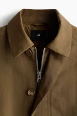 Campera de sarga levemente acolchada con cuello inglés, cierre frontal y solapa con botones. Presenta mangas raglán, bolsillos insertados delanteros y cordón ajustable en el bajo.