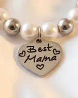 Pulsera elástica compuesta por una alternancia de perlas blancas y esferas metálicas plateadas.