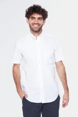 Camisa de manga corta color celeste claro, con cuello abotonado (button-down) y un bolsillo de parche en el pecho.