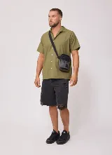 Bandolera Rusty Garin de color gris oscuro y negro, con cierre superior, bolsillo frontal y correa ajustable.