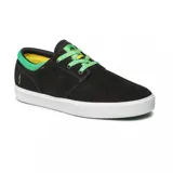 Championes de skate Emerica modelo Figgy G6 en colaboración con Shake Junt. Diseño de perfil bajo en color negro con detalles en verde vibrante en el cuello y la etiqueta de la lengüeta, montados sobre una suela blanca vulcanizada.