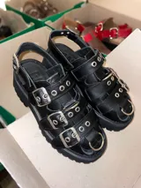 Sandalias negras de cuero vacuno con suela track y múltiples hebillas plateadas.