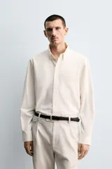 Camisa de corte relajado confeccionada en tejido de algodón, con cuello solapa, manga larga con puños abotonados, bolsillo frontal en el pecho y cierre de botonadura.