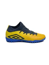 Championes de fútbol 5 Umbro modelo Ignis TF, con diseño de corte medio en tejido elástico color azul marino y cuerpo texturizado en color amarillo. Presenta suela de goma con tapones pequeños para césped sintético y logo de la marca en el lateral.