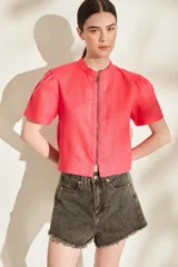 Blusa de lino color amarillo, con cuello mao, cierre frontal con cremallera y mangas cortas abullonadas. Cuenta con un bolsillo aplicado en el frente.