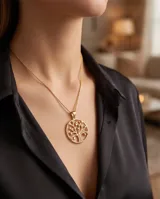 Collar de bronce dorado con cadena fina y dije circular con diseño del árbol de la vida con detalles brillantes.
