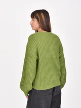 Buzo de tejido de punto grueso en color verde, con cuello redondo, mangas largas y corte holgado.