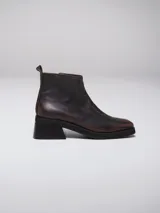 Bota corta de cuero negro con acabado efecto envejecido, punta cuadrada y tacón geométrico. Cuenta con cierre lateral para un calce práctico.