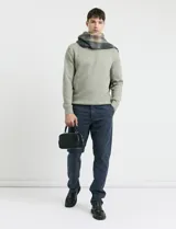 Sweater de punto en color verde claro, con cuello redondo y mangas largas. Presenta un diseño clásico de tejido liso con puños y ruedo acanalados.