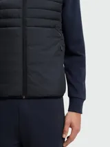 Chaleco acolchado Boss modelo Urbanex, color negro, con cierre frontal completo, cuello alto y diseño híbrido con paneles horizontales en la parte superior.
