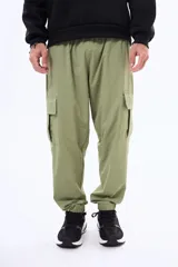 Pantalon cargo color verde oliva, de corte holgado, con bolsillos laterales con solapa y puños elásticos en los tobillos.