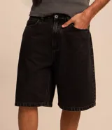 Bermuda de jean estilo baggy, color negro gastado, con bolsillos, cierre de botón y cremallera, y pespuntes contrastantes.
