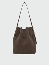 Cartera tipo bucket bag de hombro Longchamp modelo Le Roseau Velvety M, confeccionada en cuero marrón con textura de gamuza. Cuenta con correa de hombro ajustable y detalle de cierre de barrita metálica con el distintivo de la marca.