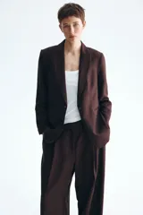 Blazer de botonadura sencilla en mezcla de lino color marrón. Modelo entallado con hombreras, solapas de pico, bolsillos delanteros ribeteados, un botón de cierre y forro interior.