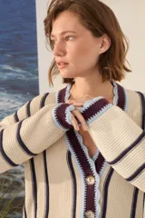 Cardigan de punto a rayas verticales en tonos marrón chocolate, blanco y amarillo, con escote en V, mangas largas y cierre frontal con botones.