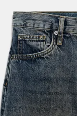 Jeans de tiro alto con corte barrel y diseño tapered, confeccionados en denim con efecto lavado y detalle de raya planchada. Presentan cintura con trabillas, cierre frontal con cremallera y botón, y bolsillos funcionales en delantero y espalda.