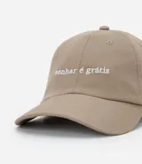 Gorra de algodón en color beige con visera curva y frase bordada en el frente. Cuenta con ajuste posterior mediante hebilla metálica.