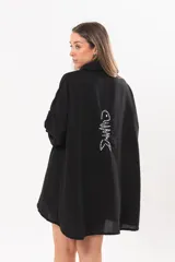 Vestido camisero corto negro, con escote en V, cuello clásico, mangas tres cuartos regulables y detalle de pez bordado a mano en la espalda.