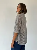 Camisa de punto calado color pistacho con hilos de lurex. Posee cuello camisero, botones frontales, mangas cortas y bolsillos delanteros.