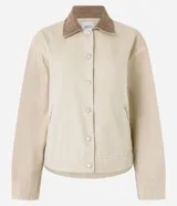 Campera worker color beige, confeccionada en sarga de algodón con cuello marrón contrastante de pana. Tiene bolsillos laterales y cierre frontal con botones.