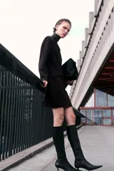 Vestido corto de sarga color marrón oscuro, con escote redondo, manga larga y cintura entallada con pinzas. Presenta bolsillos ribeteados con solapa en la parte delantera.