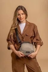 Bandolera pequeña de diseño moderno, confeccionada en tafeta liviana y resistente. Cuenta con cierre superior, correa ancha ajustable y logo frontal de la marca.