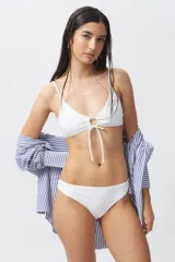 Top de bikini blanco con escote halter, abertura circular en el centro y lazos ajustables.