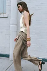 Pantalón de tiro medio con detalle de pareo superpuesto en la cintura y cierre de lazo lateral. Presenta pierna ancha y corte recto.