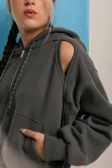 Campera negra con cierre frontal, capucha y mangas largas con aberturas en los hombros.