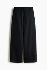 Pantalón de corte holgado en popelina de algodón, color negro, con cintura elástica y cordón de ajuste. Presenta piernas rectas, franjas de encaje en los laterales y ribete de encaje en los bajos.