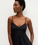 Vestido midi evasê marrón con breteles finos, escote corazón y corte en la cintura. Presenta silueta fluida con caída amplia y bolsillos laterales.