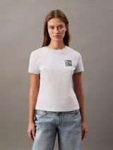 Remera blanca de algodón con elastano, corte slim, mangas cortas, cuello redondo y estampado floral en el pecho.