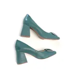 Zapato de cuero color verde, estilo stiletto con punta cuadrada y aplique metálico en el empeine. Posee un taco ancho de altura media con textura geométrica.