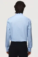 Camisa de manga larga color celeste claro, con cuello italiano y tapeta lisa con botones blancos. Presenta un corte ajustado (slim fit) y bajo redondeado.