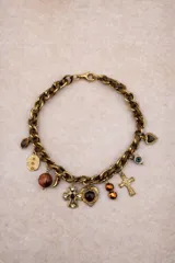 Collar de cadena de eslabones gruesos en tono dorado, adornado con múltiples dijes colgantes que incluyen cruces, corazones, esferas de cristal y otros elementos decorativos.