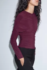 Body de manga larga con cuello en pico y diseño completamente fruncido. Presenta cierre inferior con botones a presión.