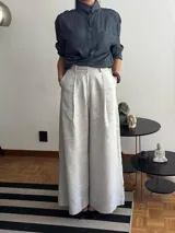 Pantalón de tiro alto con corte wide leg y caída fluida. Presenta pinzas frontales, cierre con botón y bolsillos laterales.