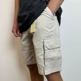 Bermuda cargo gris oscuro de gabardina, con bolsillos laterales y traseros con solapa.