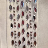 Pantalón sastrero de corte recto y cintura media con elástico en la parte posterior. Presenta una banda lateral decorativa con pedrería brillante a lo largo de ambas piernas, bolsillos laterales y cierre frontal con botón.