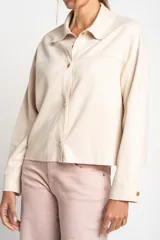 Camisa color crema de gamuza vegana, corte oversize, manga larga y cierre con botones.