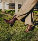 Bota de cuero vacuno color marrón con cierre lateral, taco de madera de 7cm y caña de 19cm.